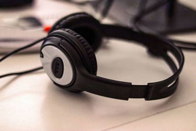 Black wired over-ear headset with a microphone resting on a light desk surface.