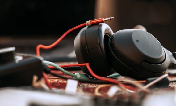 Close-up of black over-ear headphones with a red cable resting on a desk.